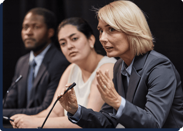 Woman speaking at panel discussion with two colleagues
